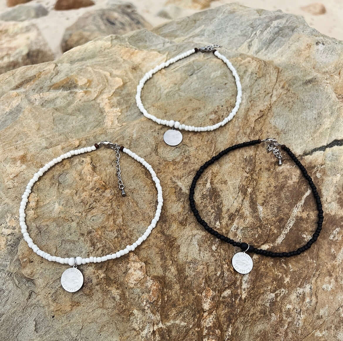 Aquarius Reef beaded choker necklaces. Photo of two all white chokers, 'Nautical', and one all black choker, 'Revenge'.