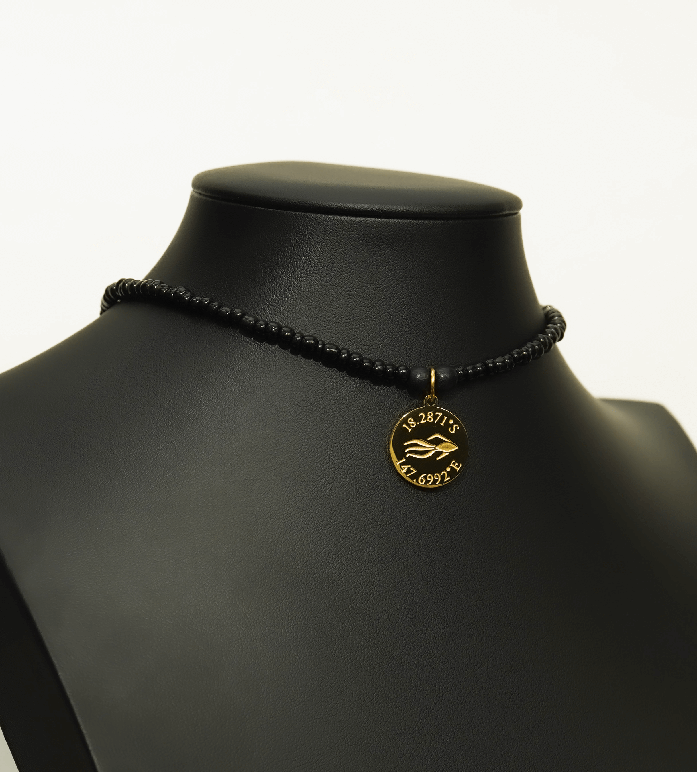 Aquarius Reef's gold 'Revenge' choker - an all black unisex seed beaded choker necklace in gold from Aquarius Reef's Edge collection, featuring a pendant with coordinates of the Great Barrier Reef. 