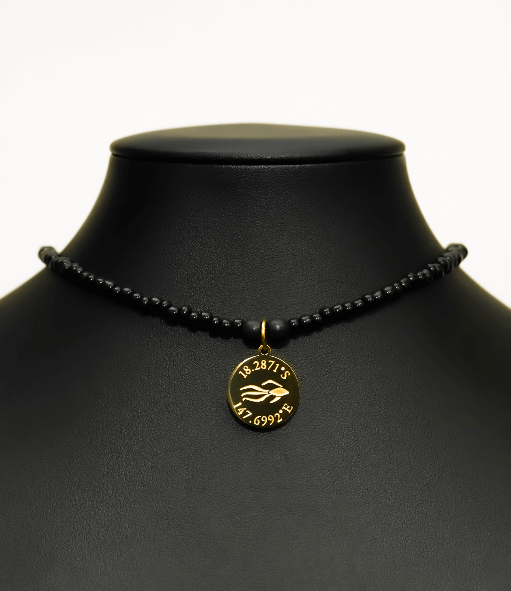 Aquarius Reef's gold 'Revenge' choker - an all black unisex seed beaded choker necklace in gold from Aquarius Reef's Edge collection, featuring a pendant with coordinates of the Great Barrier Reef. 