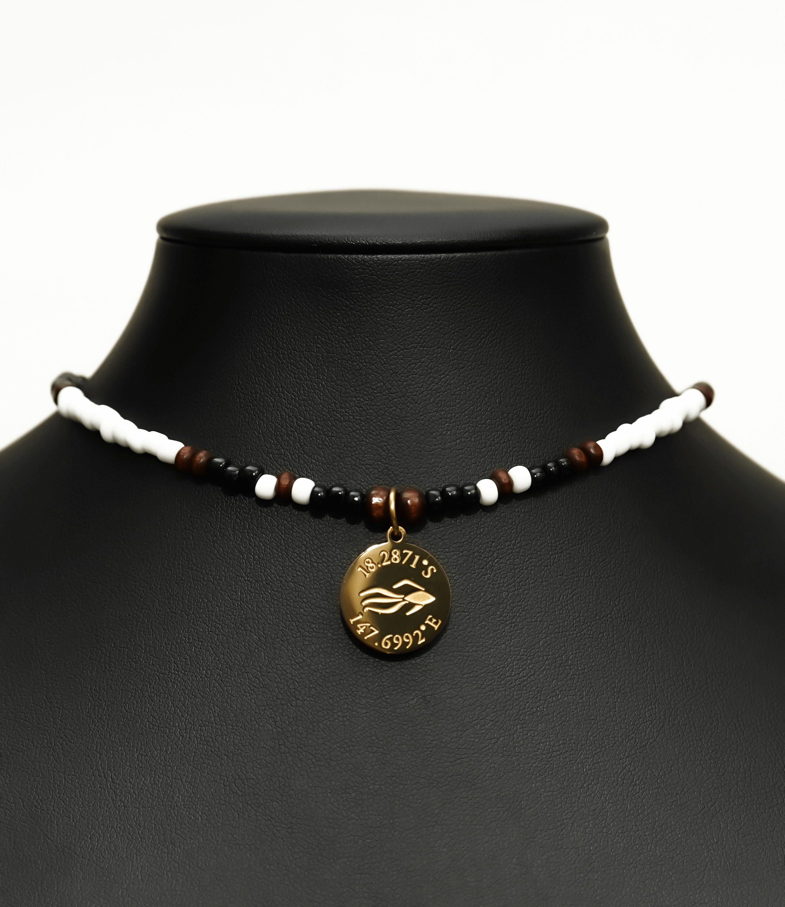 Aquarius Reef's gold 'Sparrow' choker - a black and white patterned unisex seed beaded choker necklace in gold from Aquarius Reef's Edge collection, featuring a pendant with coordinates of the Great Barrier Reef. 